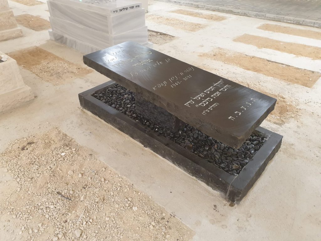 מצבה יחידה בעיצוב מרחף על גבי אבנים במסגרת פראית משיש גרניט שחור